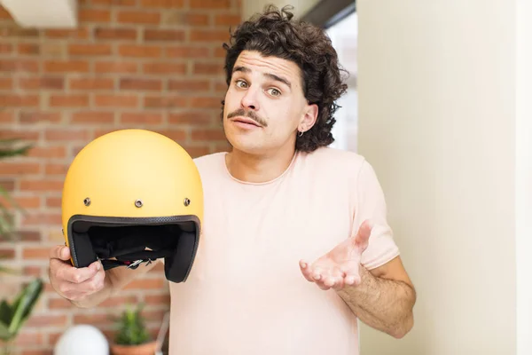 若いハンサムな男が家の中でバイクのヘルメットを持って — ストック写真
