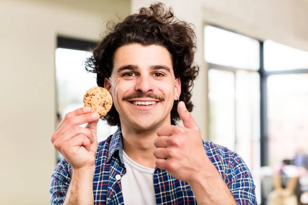 自宅のインテリアで手作りのクッキーを持つ若いハンサムな男 — ストック写真