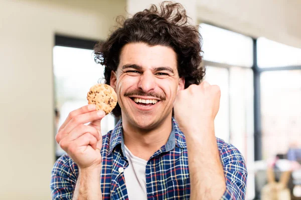 自宅のインテリアで手作りのクッキーを持つ若いハンサムな男 — ストック写真