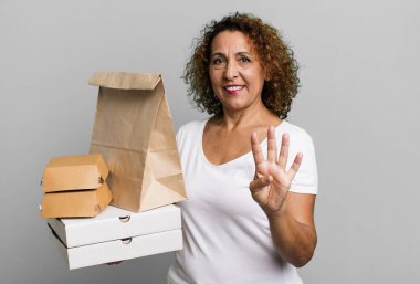 Gülümsüyor ve dost canlısı görünüyor, dört numarayı gösteriyor. Fast food dağıtım konseptini kaldır..