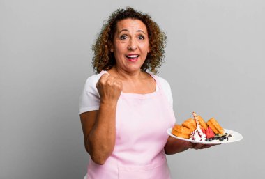 Oldukça orta yaşlı bir kadın şokta, gülüyor ve başarıyı kutluyor. Ev yapımı waffle konsepti