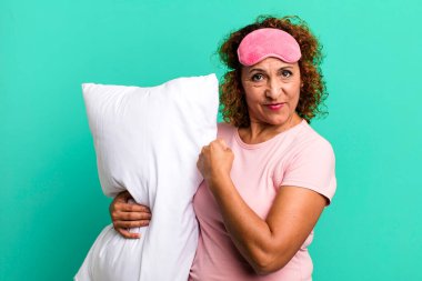 Güzel, orta yaşlı bir kadın mutlu ve zorluklarla yüzleşiyor ya da pijama ve yastık giyerek kutlama yapıyor.