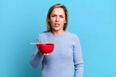 pretty blonde woman feeling puzzled and confused. japanese noodles concept