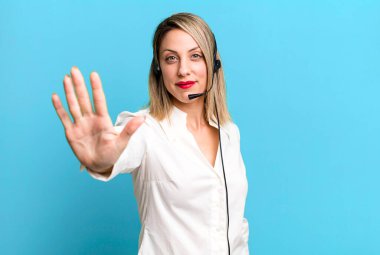 pretty blonde woman smiling and looking friendly, showing number five. telemarketer concept