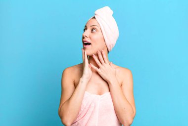 Güzel sarışın kadın mutlu, heyecanlı ve şaşırmış hissediyor. Bornoz ve güzellik konsepti