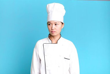 pretty asian woman feeling sad, upset or angry and looking to the side. restaurant chef concept