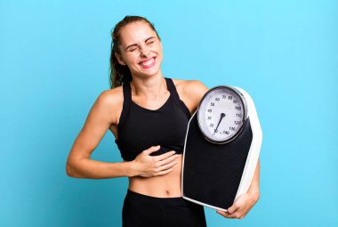 hispanic pretty woman laughing out loud at some hilarious joke. fitness, diet and weight scale concept