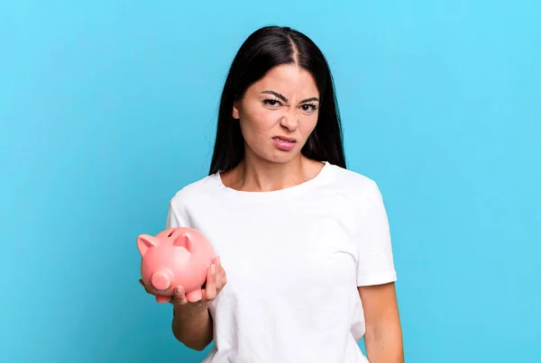 Hispanic Pretty Woman Feeling Puzzled Confused Piggy Bank — Stockfoto
