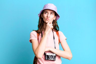 Genç, güzel bir kadın düşünüyor, kuşkulu ve şaşkın hissediyor. turizm konsepti