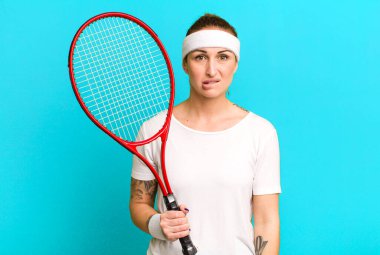 young pretty woman looking puzzled and confused. tennis concept