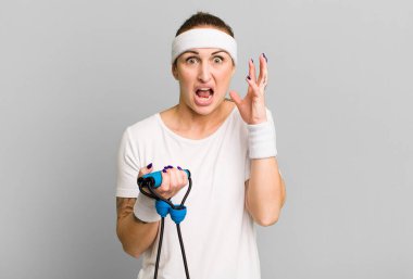 Genç ve güzel bir kadın ellerini havaya kaldırarak çığlık atıyor. fitness konsepti