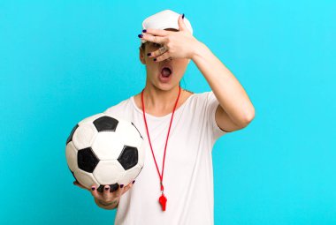 young pretty woman looking shocked, scared or terrified, covering face with hand. soccer coach concept