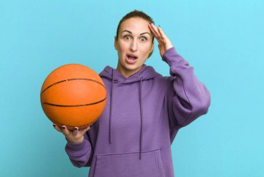 young pretty woman looking happy, astonished and surprised. basketball concept