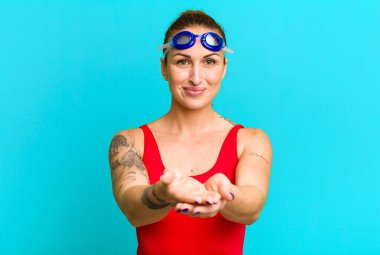 Genç ve güzel bir kadın arkadaşça gülümsüyor ve bir konsept sunuyor. yüzücü kavramı