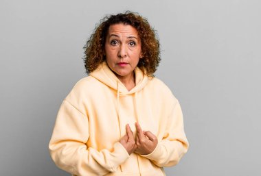 Orta yaşlı İspanyol bir kadın, şaşkın ve şaşkın bir bakışla kendini işaret ediyor. Seçildiğim için şaşırmış ve şaşırmış.