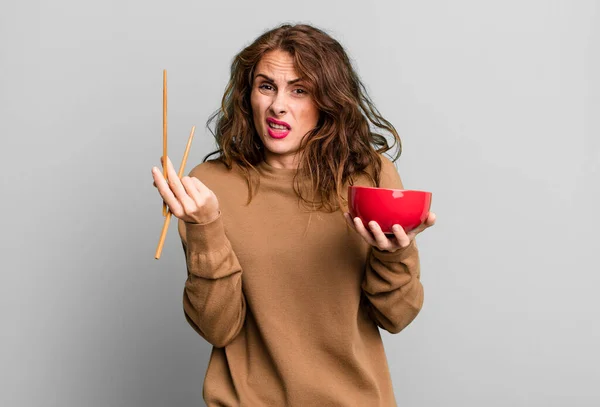 stock image hispanic pretty young woman eating a japanese noodles bowl.