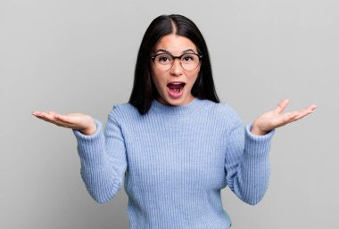 Güzel Latin bir kadın mutlu, heyecanlı, şaşırmış ya da şok olmuş, gülümseyen ve hayrete düşmüş.