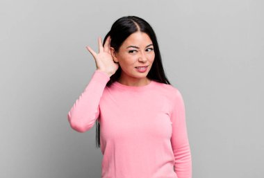 Güzel Latin bir kadın ciddi ve meraklı görünüyor, dinliyor, gizli bir konuşma veya dedikodu duymaya çalışıyor, kulak misafiri oluyor.