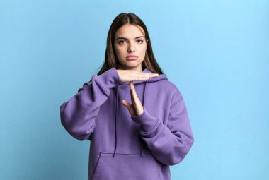 pretty young adult woman looking serious, stern, angry and displeased, making time out sign