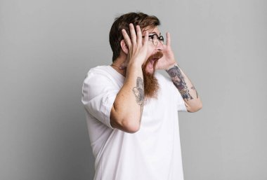 Uzun sakal ve kızıl saçlı adam mutlu, heyecanlı ve şaşırmış hissediyor.