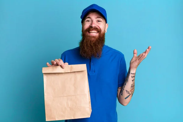 若い大人の赤い髪の髭のクールな配達人と紙袋 — ストック写真