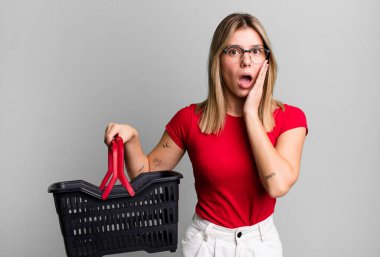 Genç ve güzel bir kadın şok olmuş ve korkmuş hissediyor. boş alışveriş sepeti kavramı