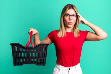 Genç, güzel bir kadın şaşırmış görünüyor, yeni bir düşünce, fikir ya da konsept fark ediyor. boş alışveriş sepeti kavramı