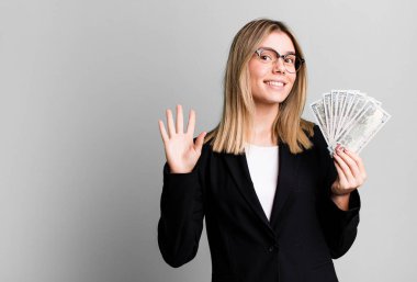 Genç ve güzel bir bayan mutlu bir şekilde gülümsüyor, el sallıyor, sizi selamlıyor ve selamlıyor. iş ve para kavramı