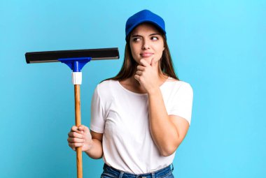 young pretty woman smiling with a happy, confident expression with hand on chin. cleaning windows concept