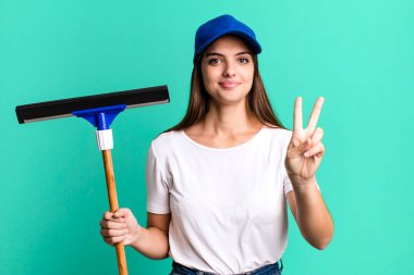 Genç, güzel bir bayan gülümsüyor ve iki numarayı gösteriyor. Pencere temizleme kavramı