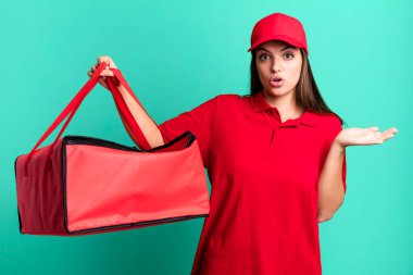 Genç ve güzel bir kadın şaşırmış ve şok olmuş görünüyor. Çenesi düşmüş ve elinde bir nesne tutuyor. Pizza teslimatı kavramı