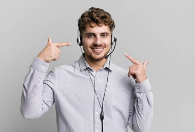 Genç, beyaz, kendine güvenen bir adam kendi gülüşünü işaret ediyor. tele pazarlamacı ajan konsepti