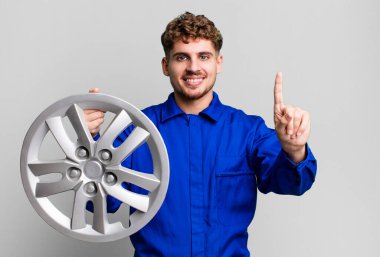 Genç, beyaz bir adam gülümsüyor ve arkadaş canlısı görünüyor. Bir numarayı gösteriyor. araba tamircisi veya mekanik konsepti