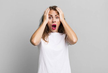 Genç ve güzel bir kadın hoş olmayan bir şekilde şok olmuş, korkmuş ya da endişeli görünüyor ağzı sonuna kadar açık ve iki kulağını da elleriyle kapatıyor.