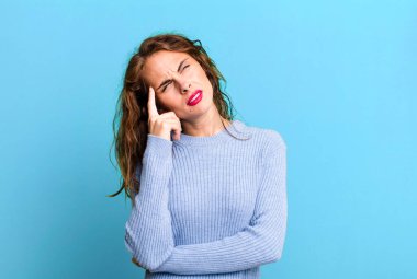 Yoğunlaşmış bakışları olan genç ve güzel bir kadın şüpheli bir ifadeyle yukarı ve yana bakıyor.