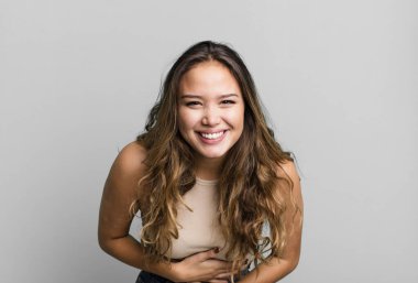 Genç ve güzel bir kadın komik bir şakaya yüksek sesle gülüyor, mutlu ve neşeli hissediyor, eğleniyor.