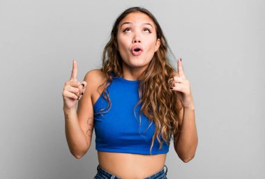 Genç ve güzel bir kadın huşu içinde ve ağzı açık bir şekilde şaşkın ve şaşkın bir bakışla yukarıya bakıyor.