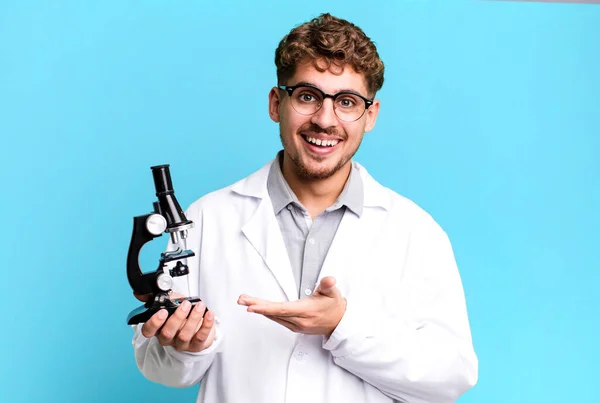 若い大人の白人男性は陽気に笑って幸せを感じコンセプトを示しています 顕微鏡の概念を持つ科学研究室の学生は — ストック写真