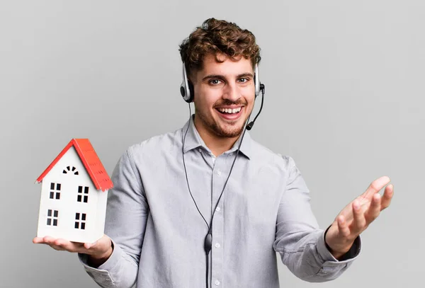 年轻的白人成年人 带有耳机和房屋模型的真正的国家代理 — 图库照片