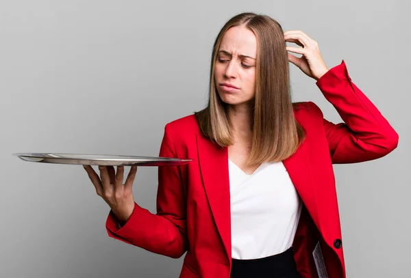 feeling puzzled and confused, scratching head. businesswoman presenting with a tray