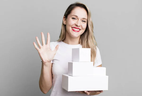 stock image smiling and looking friendly, showing number five. white boxes concept