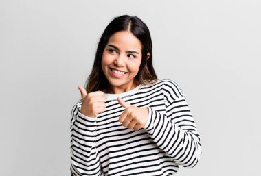 İspanyol güzel kadın neşeyle gülümsüyor ve yan taraftaki fotokopi alanını gösteriyor, mutlu ve tatmin olmuş hissediyor.