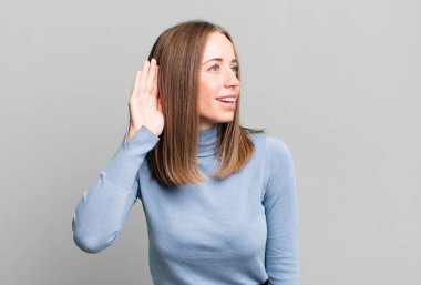 Gülümsüyor, tuhaf bir şekilde yan tarafa bakıyor, dedikoduları dinlemeye ya da bir sırrı duymaya çalışıyor.