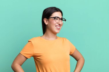 Mutlu, neşeli ve kendinden emin görünüyor, gururla gülümsüyor ve iki elini de kalçasında tutuyor.