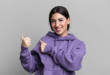 Neşeli bir şekilde gülümsüyor ve yan taraftaki fotokopi alanını işaret ediyor, mutlu ve tatmin olmuş hissediyordu.