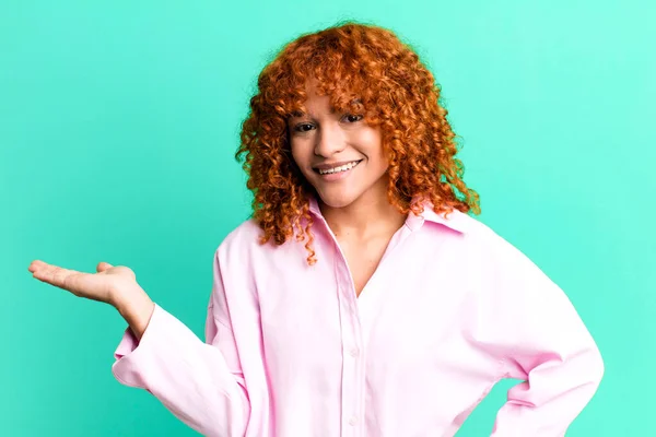 stock image redhair pretty woman smiling, feeling confident, successful and happy, showing concept or idea on copy space on the side