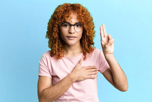 stock image redhair pretty woman looking happy, confident and trustworthy, smiling and showing victory sign, with a positive attitude