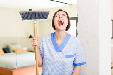 young pretty woman shouting aggressively, looking very angry. housekeeper concept