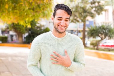 Genç İspanyol adam komik bir şakaya yüksek sesle gülüyor, mutlu ve neşeli hissediyor, eğleniyor.