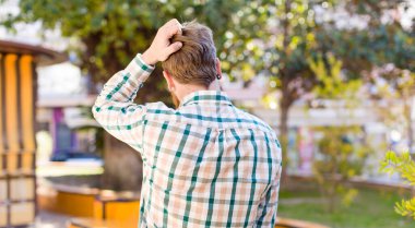 Kızıl sakallı adam düşünüyor ya da şüphe ediyor, kafasını kaşıyor, kafası karışık ve kafası karışık hissediyor, arkaya ya da arkaya bakıyor.